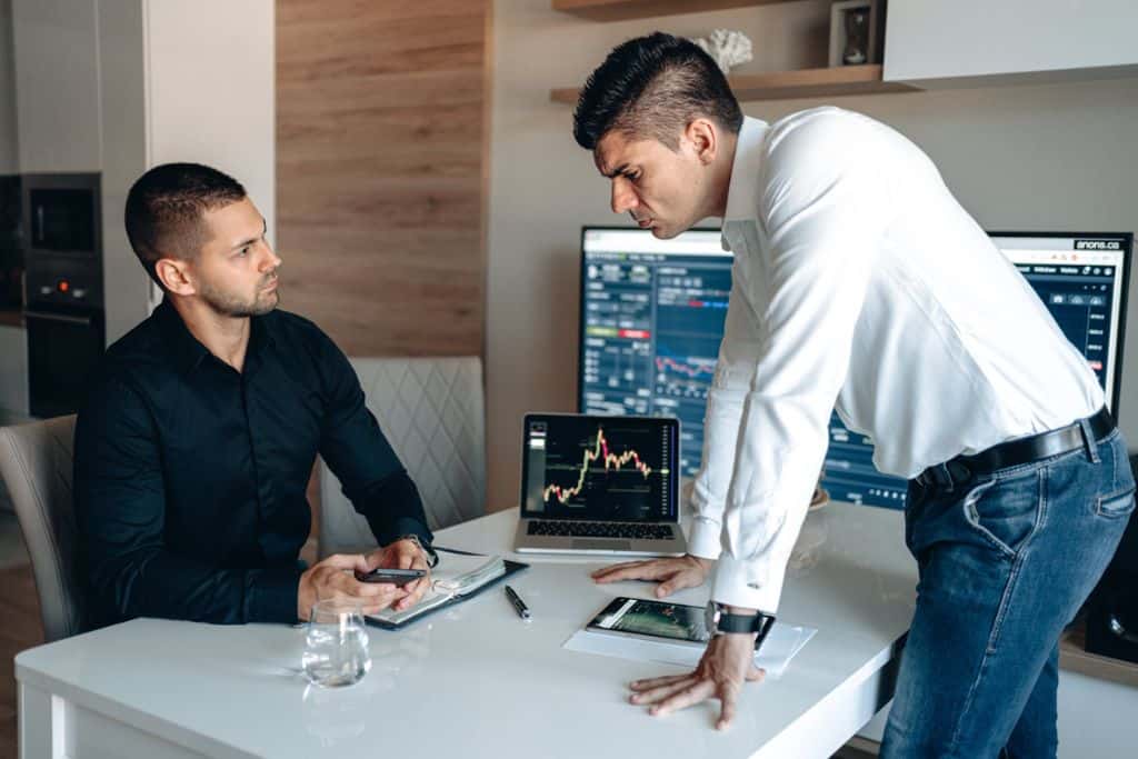 Two men keeping a trade journal and discussing the stock market - TradeZella 