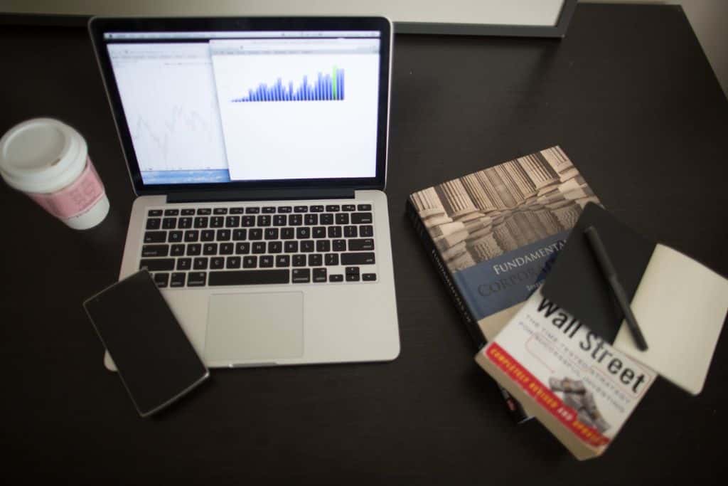  Laptop with the stock market on screen with stock market books on the right - TradeZella